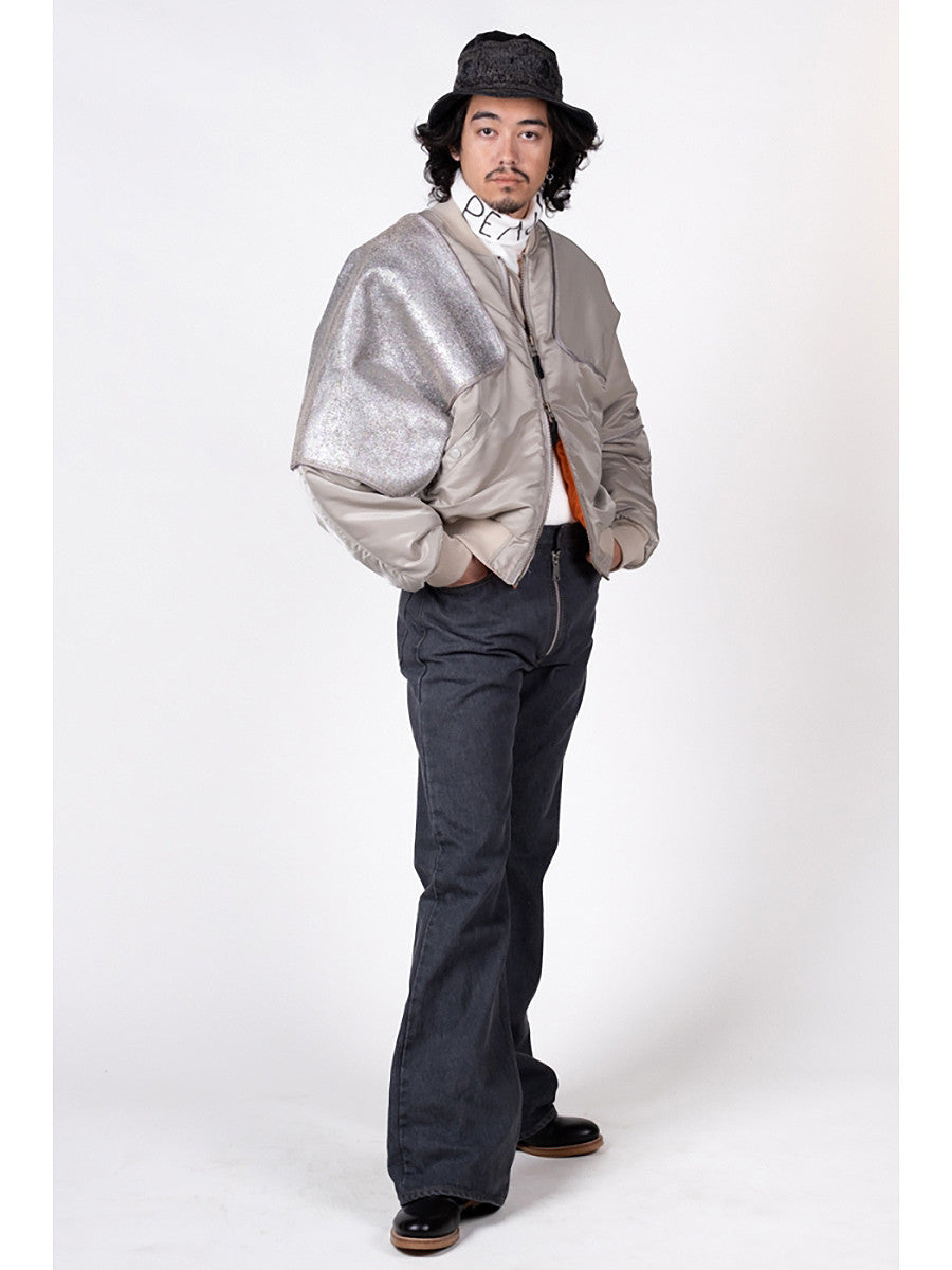 Person wearing a silver jacket and dark pants on a white background