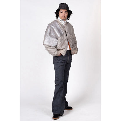 Person wearing a silver jacket and dark pants on a white background